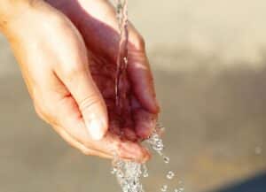 Close-up of hands catching flowing water outdoors, symbolizing freshness and purity and the sign of Aquarius.