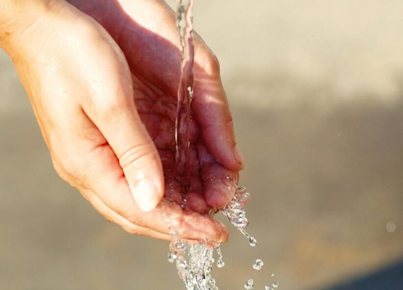 Close-up of hands catching flowing water outdoors, symbolizing freshness and purity and the sign of Aquarius.
