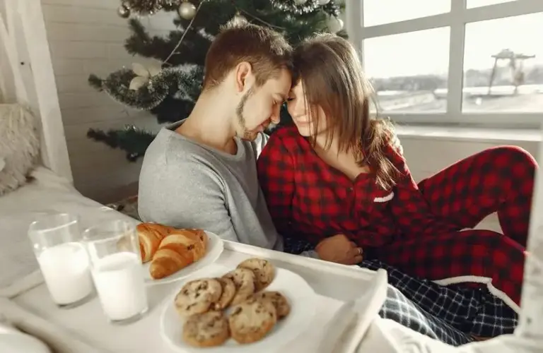 A couple sitting in front of a Christmas tree. Working to find ways to focus on romance during the busy holiday season.