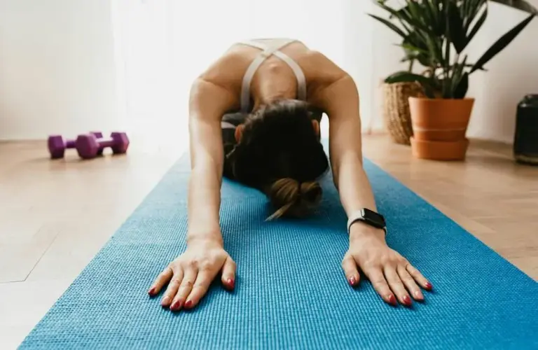 Woman stretching on a yoga mat. Yoga can be one of the great low-impact workouts for winter fitness routines.