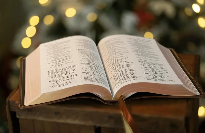 open bible with blurred christmas lights in the background. Keeping Christ in Christmas