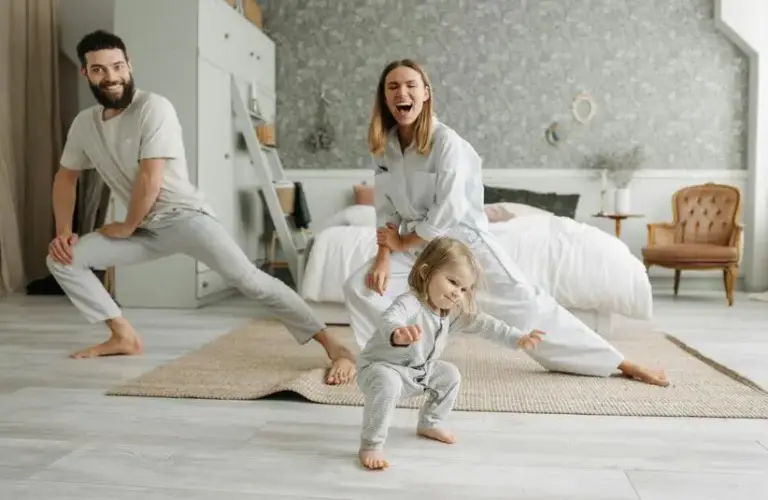 two people stretching their legs in a room with a child. getting the family involved can be one of the great indoor workouts during the cold, shorter days of the year.