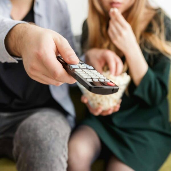 image of A couple enjoying a relaxing movie night, sitting on a sofa with popcorn and a TV remote in November