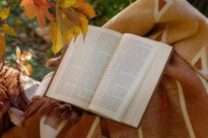 Open book on a blanket surrounded by autumn leaves for a cozy seasonal reading vibe, daily devotion