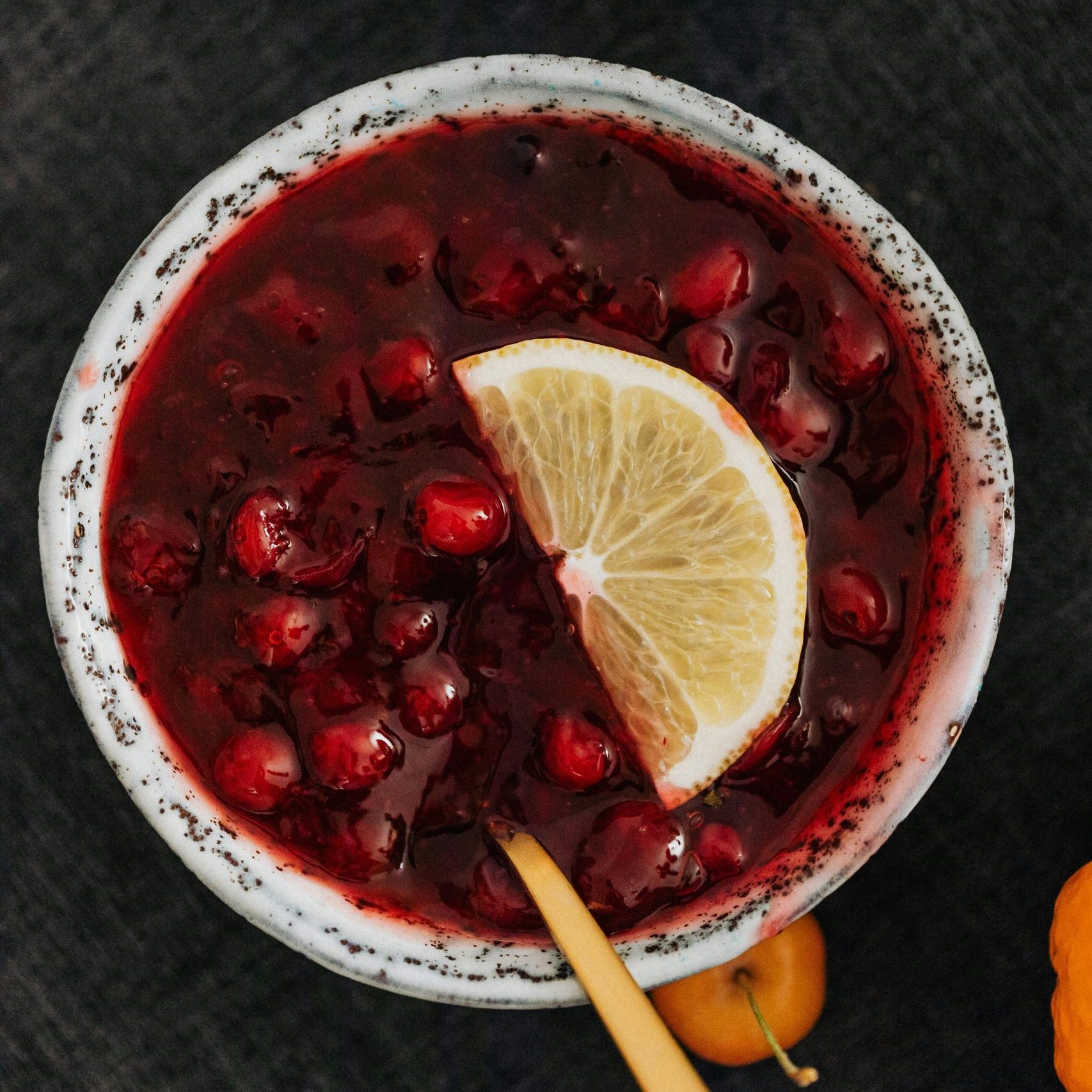 Top view of a bowl of cranberry sauce garnished with a lemon slice. Perfect Friendsgiving recipe.