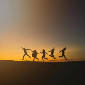 Group of friends jumping joyfully during sunset in Iceland, symbolizing freedom and happiness. A great place to travel for friendsgiving.