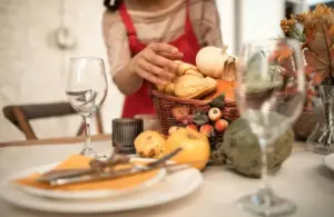 Person in a red and white long sleeve shirt in front of a table with Thanksgiving decor possibly thinking about Thanksgiving leftovers