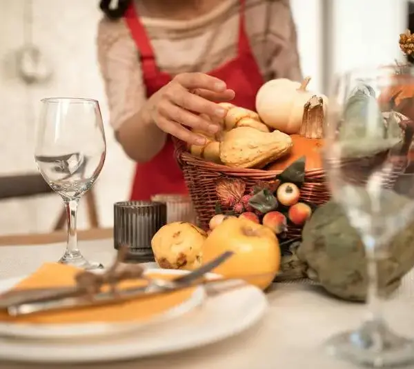 Person in a red and white long sleeve shirt in front of a table with Thanksgiving decor possibly thinking about Thanksgiving leftovers