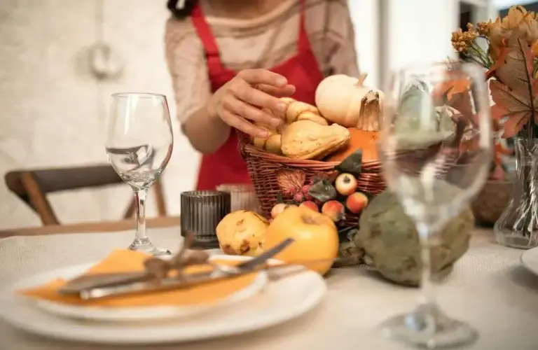 Person in a red and white long sleeve shirt in front of a table with Thanksgiving decor possibly thinking about Thanksgiving leftovers