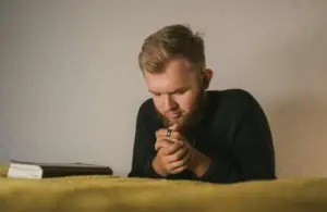 shot of a bearded mean in black knitted sweater in prayer, praying,