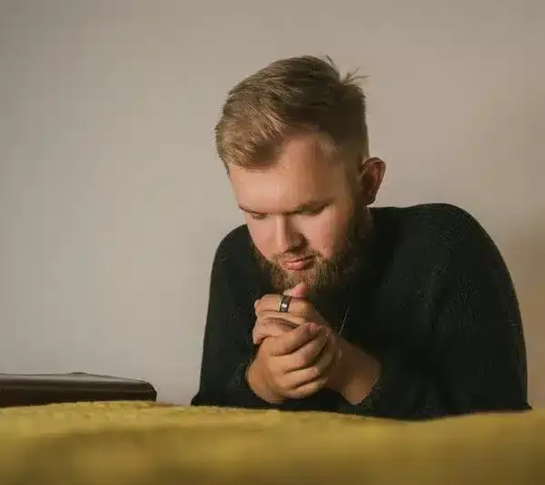 shot of a bearded mean in black knitted sweater in prayer, praying,