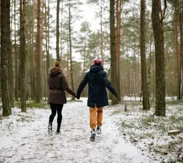 a couple holding hands outside in the cold and snow. cuffing season.