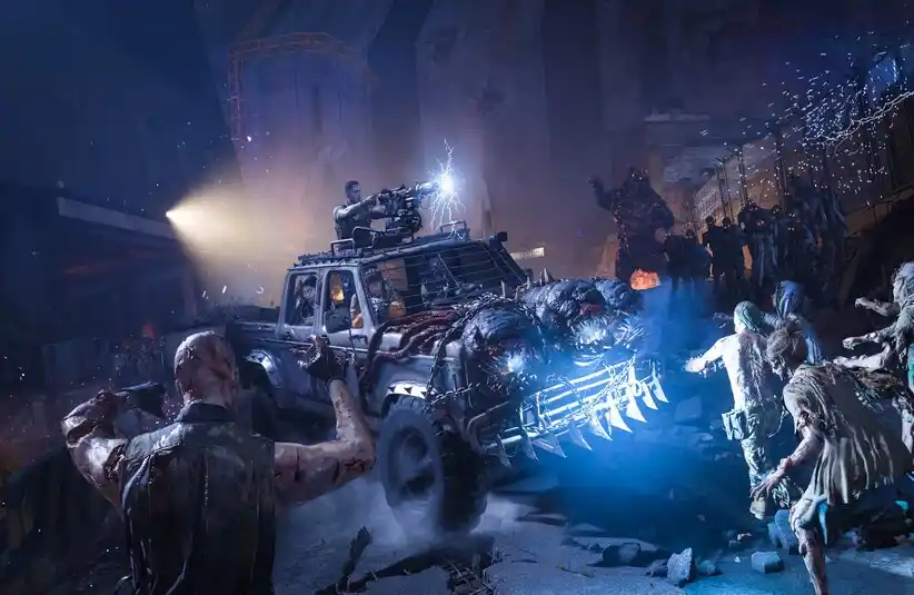 Call of Duty: Black Ops 7 Zombies. A rugged, armored truck plows through a swarm of zombies in a dark, chaotic setting. A man atop fires a mounted gun, spotlight highlighting the scene.