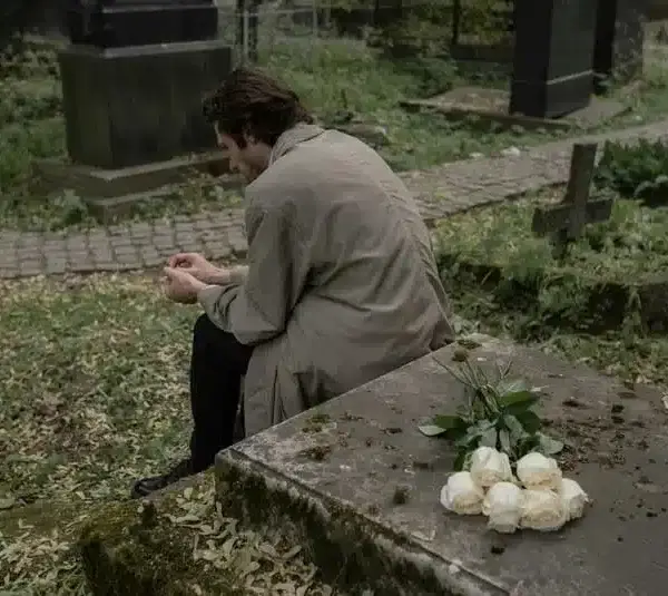 Man sitting on a grave, mourning the lost of a loved one, grief, holidays, coping methods