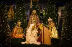 A warm, glowing nativity scene with Mary, Joseph, the Wise Men, and Christmas trees illuminated by festive lights., We Three Kings