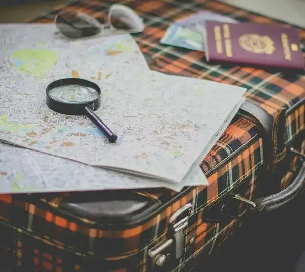 suitcase, maps, passport, & magnifying glass for travel prep,