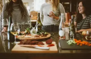 Several people at a holiday gathering sharing food and drinks in a small space