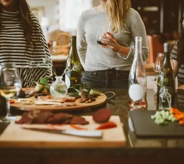 Several people at a holiday gathering sharing food and drinks in a small space