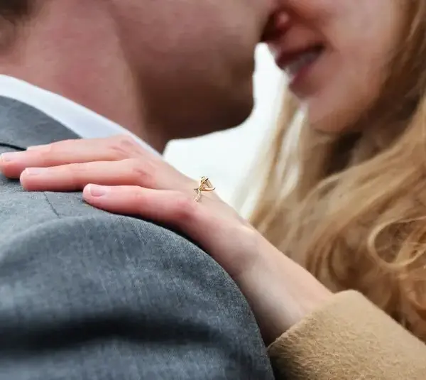 A couple embraces and showing an engagement ring on her hand, winter proposal