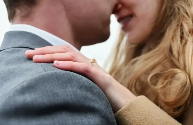 A couple embraces and showing an engagement ring on her hand, winter proposal