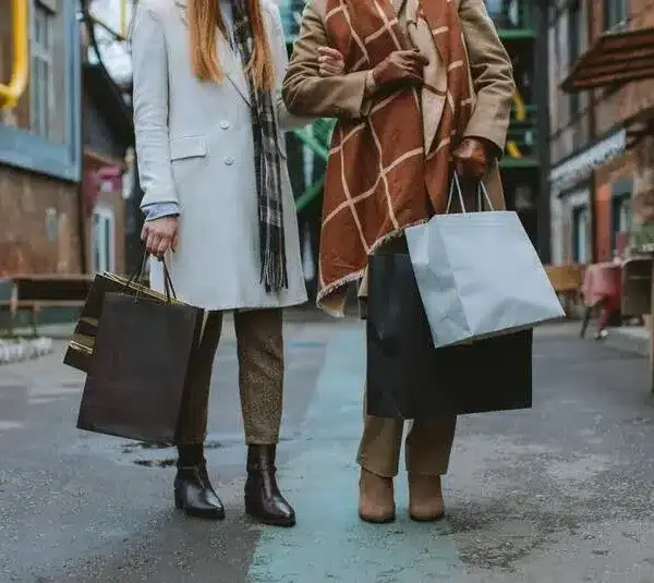 Two people in stylish winter coats and shopping bags.