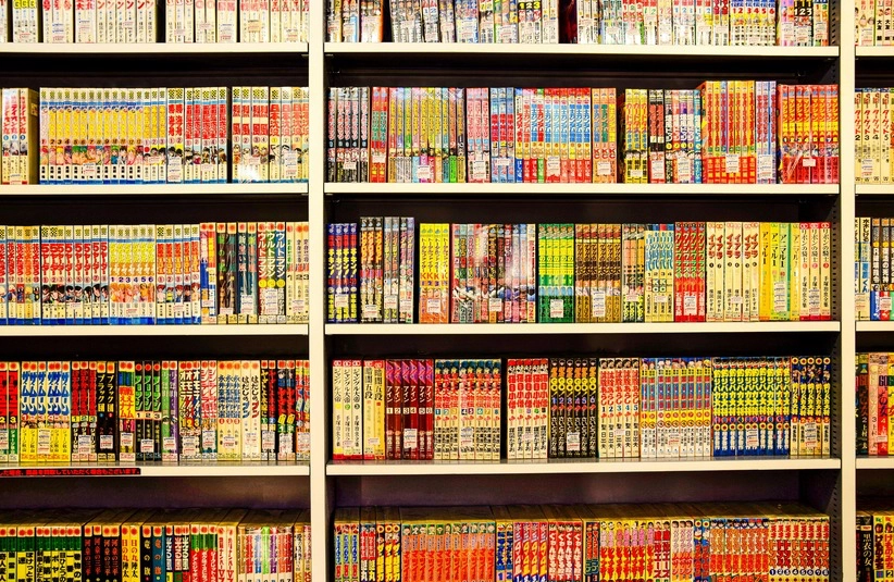 Bookshelf lined with colorful manga volumes in Japanese, organized neatly in rows. Vibrant covers create a lively and inviting atmosphere. Free Comic Book Day 2026