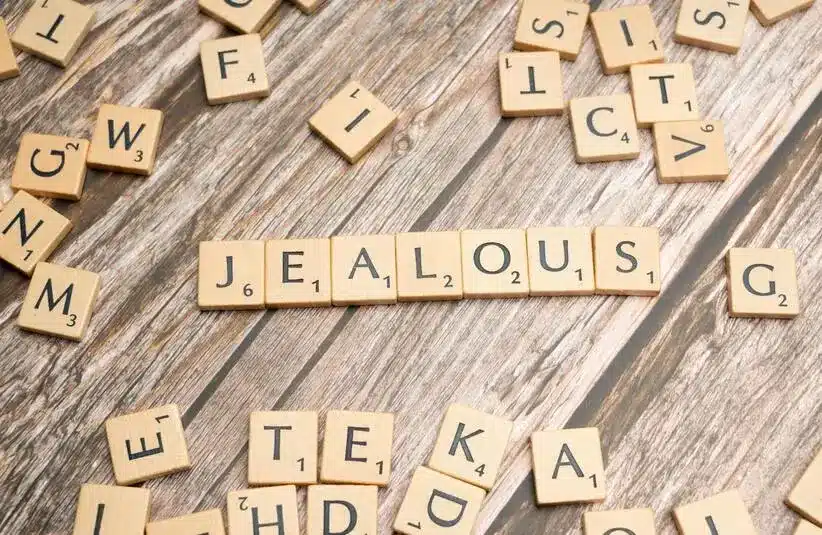 Jealous spelled out in scrabble like tiles. Holiday jealousy can be a lot to navigate