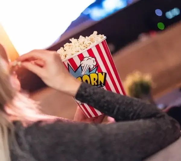 A person eating popcorn and watching tv, holiday movie night, bonding