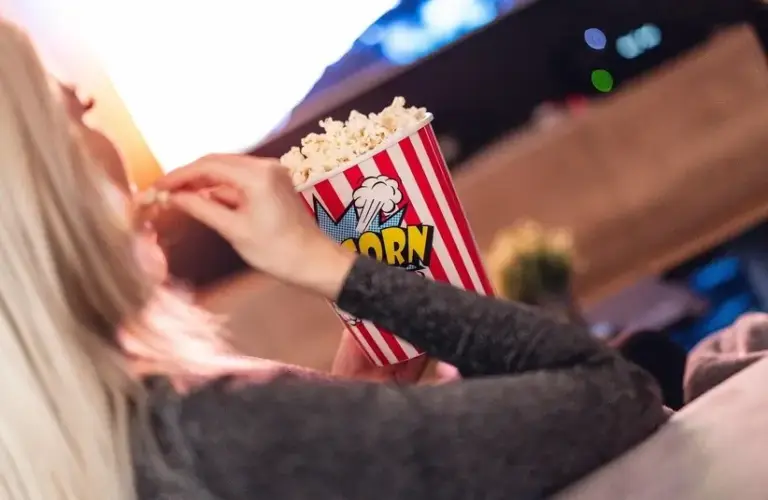 A person eating popcorn and watching tv, holiday movie night, bonding