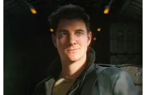 A 3D-rendered character with short dark hair smiles slightly, wearing a leather jacket in a dimly lit tunnel. Warm, soft lighting conveys a sense of adventure. 007 First Light, Courtesy of IO Interactive A/S.