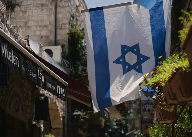 Image of the flag of Israel flying on a short pole above the entrance to a building, Genesis, Old Testament. Israel is the enemy of Hezbollah.