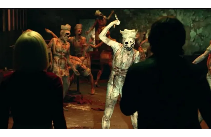"Return to Silent Hill" movie shows a dim, eerie room filled with humanoid figures in distressed nurse outfits, wearing masks. Two onlookers appear silhouetted in the foreground.