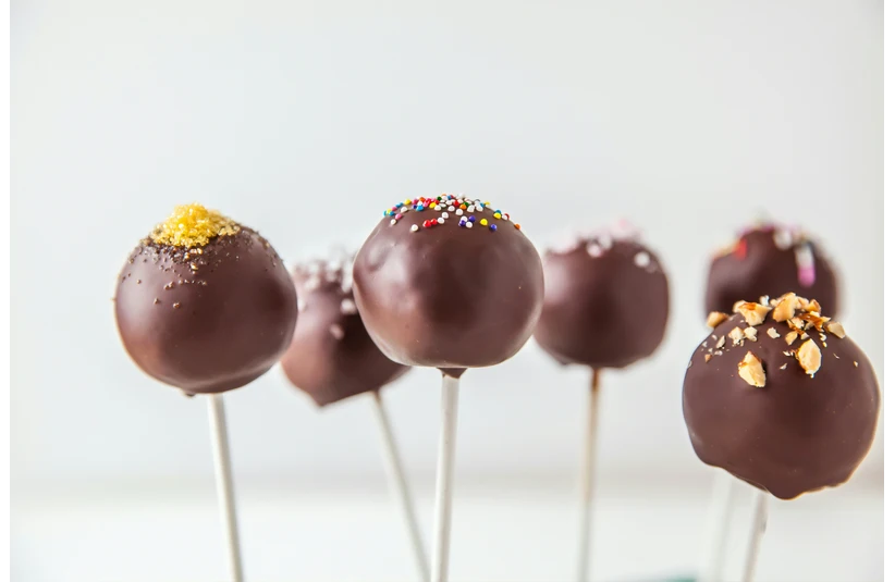 A photo of an array of chocolate cake pops with different toppings