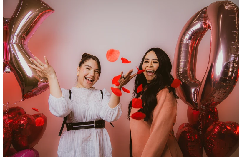 Photo of two friends throwing rose petals into the air celebrating Valentine's Day