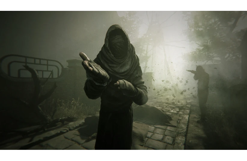 A mysterious hooded figure in Pathologic 3 reaches out on a foggy path, surrounded by swirling leaves. Another figure points in the background. Ominous and eerie atmosphere.