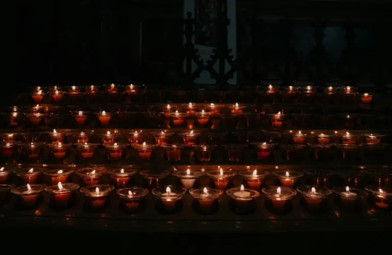 A warm cluster of lit candles glowing in a dark room, symbolizing the light and hope of Candlemas.