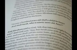 In daily devotion, a Bible is open to a passage in Genesis.
