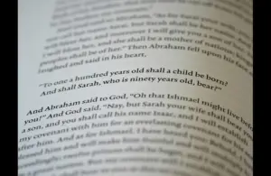 In daily devotion, a Bible is open to a passage in Genesis.