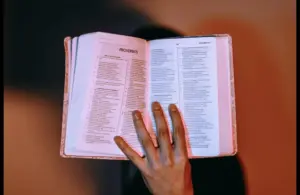 In Daily Devotion, a lady's hand is holding the BIble open to Proverbs.