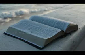 In daily devotion, an open Bible is set near a seashore.