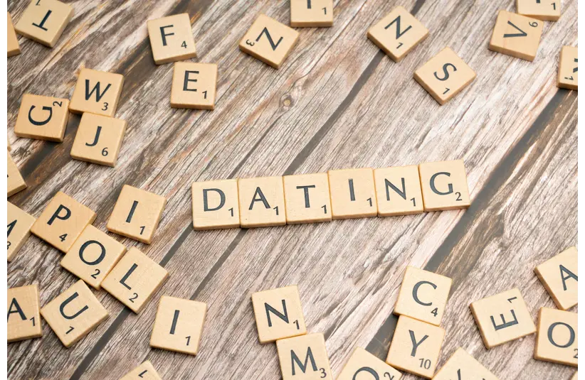 Scrabble tiles spell "DATING" on a wooden surface, emphasizing clarity dating