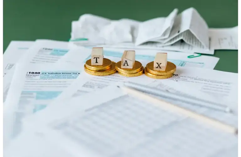 Image of TurboTax/ Tax Documents on the Table with the word "TAX" spelled out on top of the documents.