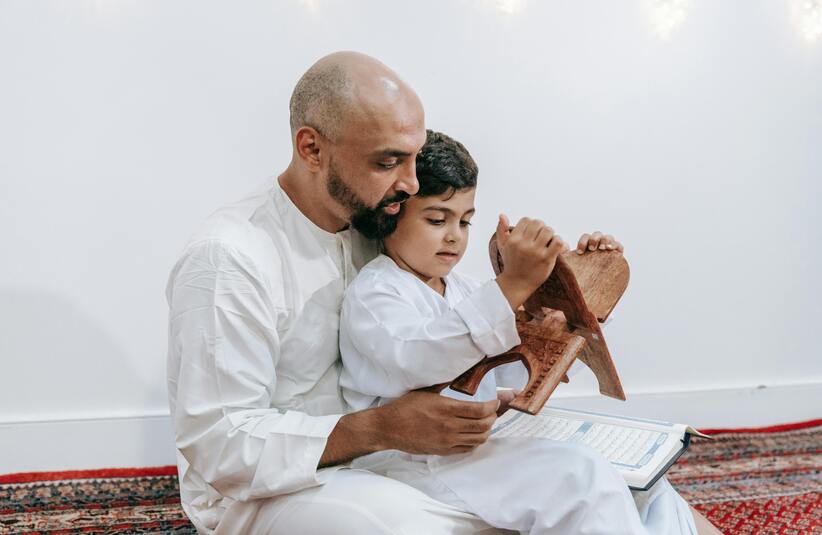 Father and son reading Koran as part of daily devotion.