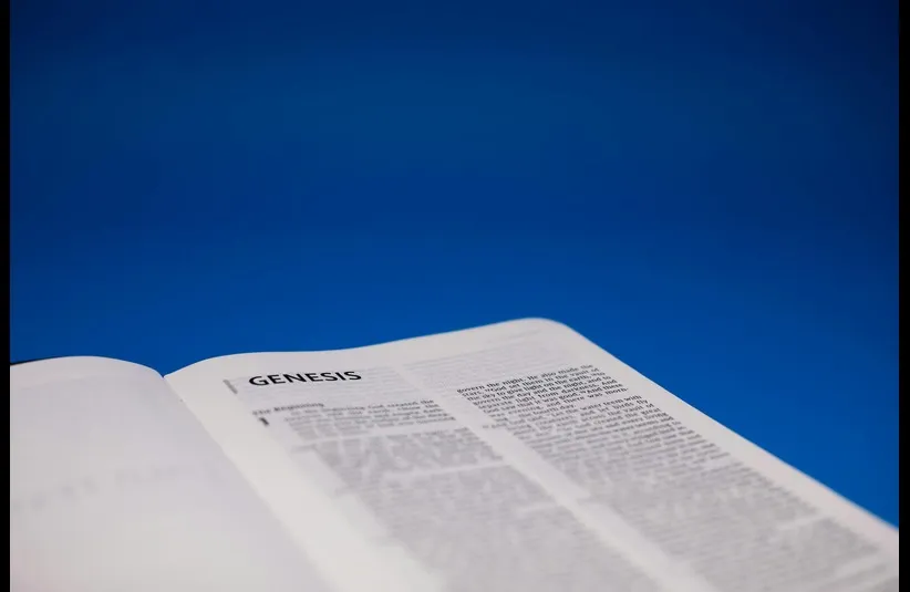 In daily devotion, a Bible is open to Genesis.