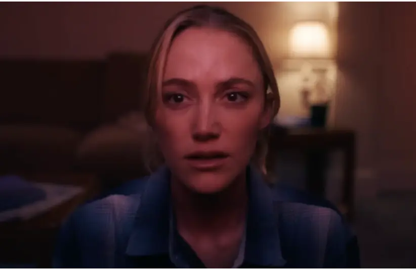 Image from Resident Evil live-action short film Evil Has Always Had A Name, showing Maika Monroe staring at an emergency broadcast on her TV