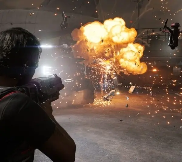 A person in Mindseye game fires a weapon at explosive barrels, causing a fiery explosion with flying debris and sparks. Drones hover nearby, creating an intense, chaotic scene.