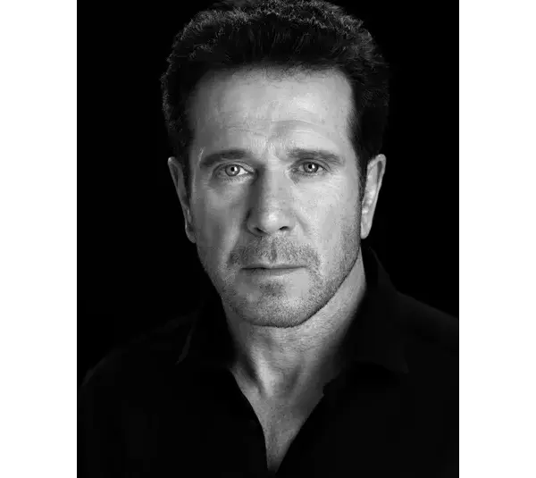A Black and white portrait of Bobby J. Brown, a serious man with short dark hair, wearing a dark shirt, against a black background, conveying intensity and focus.