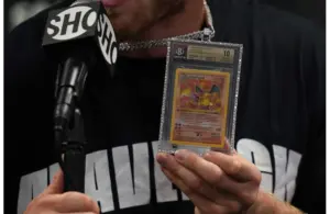 Jun 6, 2021; Miami, Florida, USA; Logan Paul holds up a Pokemon Charizard card he wears around his neck while speaking to the media after his fight against Floyd Mayweather Jr. (not pictured) at Hard Rock Stadium. Mandatory Credit: Jasen Vinlove-Imagn Images