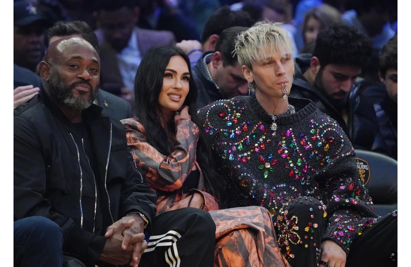 Feb 20, 2022; Cleveland, Ohio, USA; Recording artist Machine Gun Kelly (right) with wife Megan Fox (center) during the 2022 NBA All-Star Game at Rocket Mortgage FieldHouse. Fox and MGK are one of the least liked celebrity couples. Mandatory Credit: Kyle Terada-Imagn Images