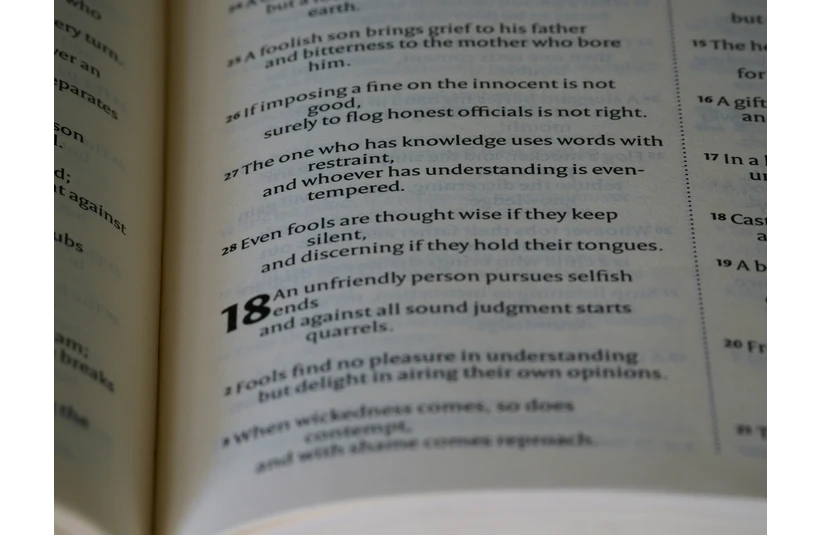 Open book showing a passage with numbered verses. Verse 18 appears bold, discussing themes of wisdom, restraint, and understanding. Calm tone. the ten commandments